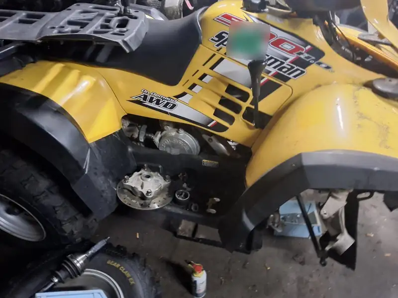 A Polaris Sportsman with the front hub off. The registration sticker is covered.