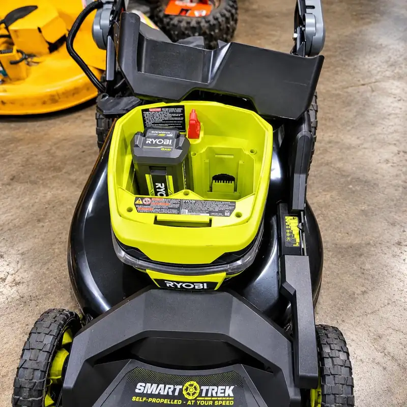 A Ryobi battery mower with the battery bay open.