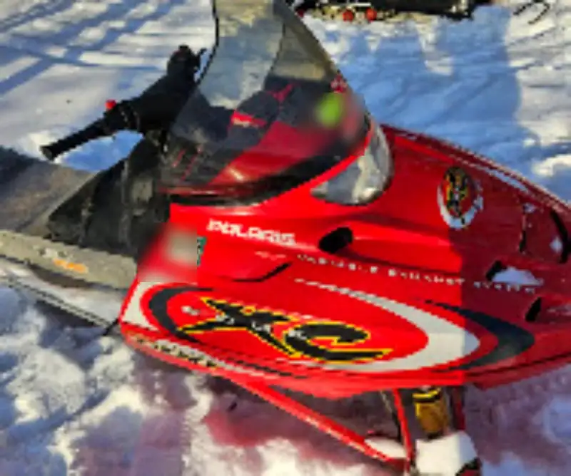 A red Polaris XC snowmobile. The registration sticker is covered.