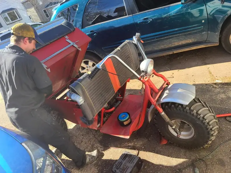 Working on a three-wheeler in the driveway.